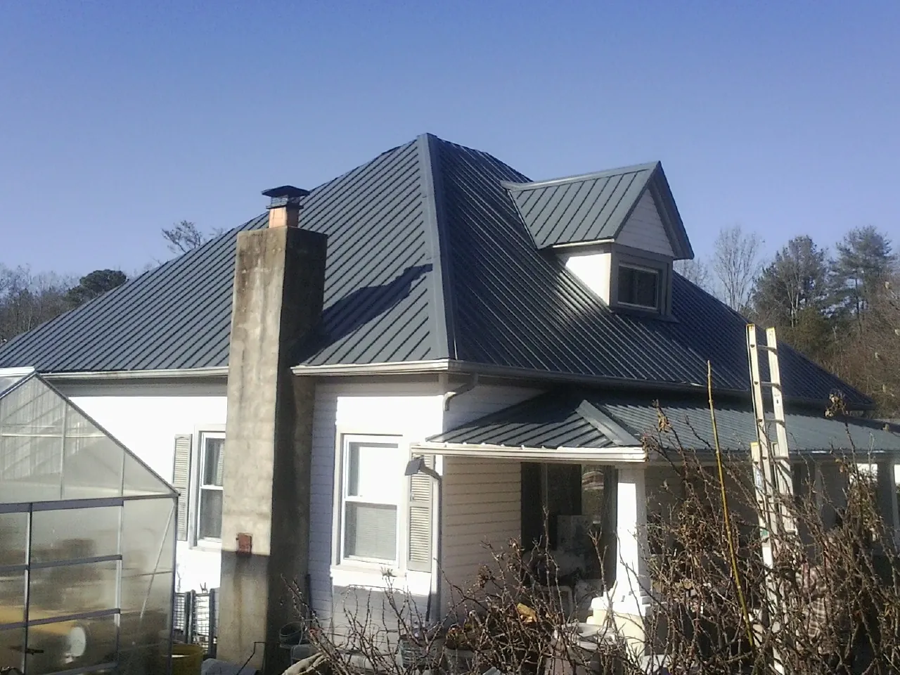 Dark blue standing seam metal roof on a white farmhouse with dormer — Slate & Tile Roof Repair by Roofing Brothers in Pedro Bay