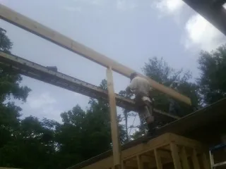 Carpenter setting a ridge beam over a new addition frame — Ice Dam Removal by Roofing Brothers in Pedro Bay