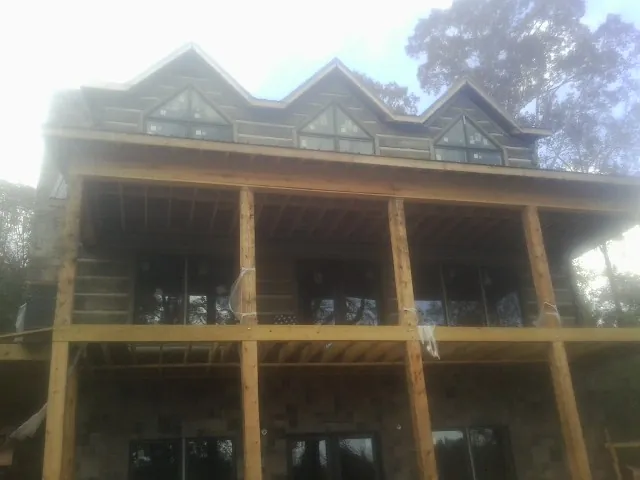Dormers and porch framing on a large log home under construction — Roof Coating work by our crew in Pedro Bay