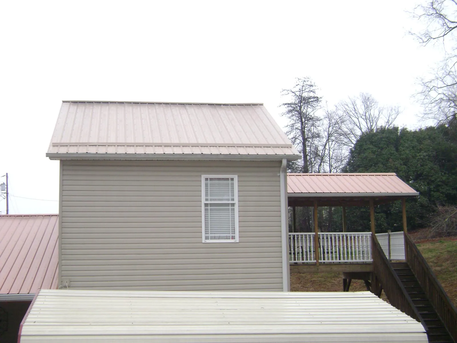 Tan metal roofs on a two story addition and attached porch, from a Roof Replacement job in Pedro Bay