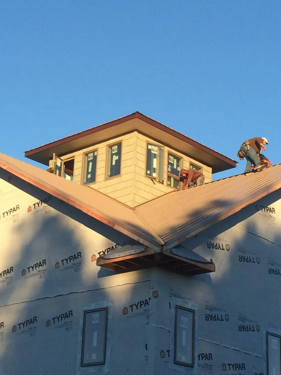 Roofers working around a rooftop cupola on a new metal roof at sunset — Roof Waterproofing in Pedro Bay by Roofing Brothers